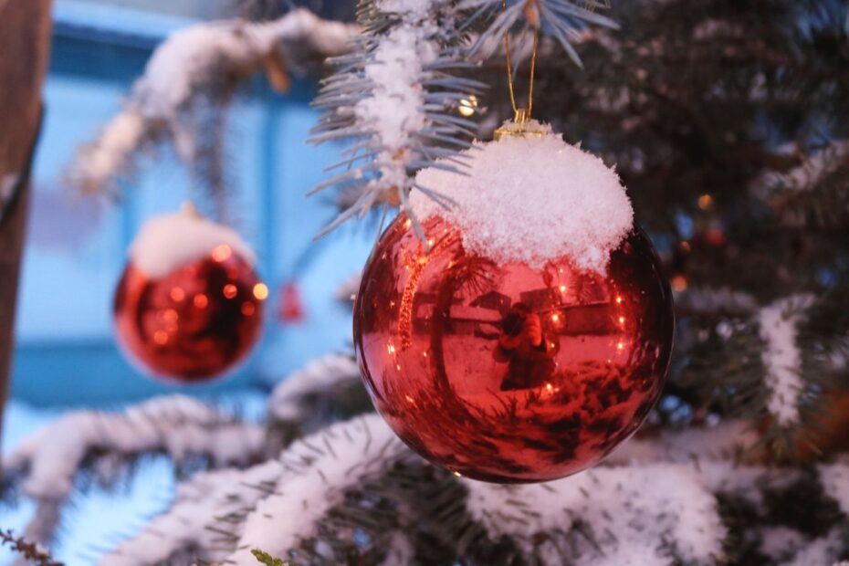 Red Christmas ornament with snow on fir tree, reflecting holiday spirit.